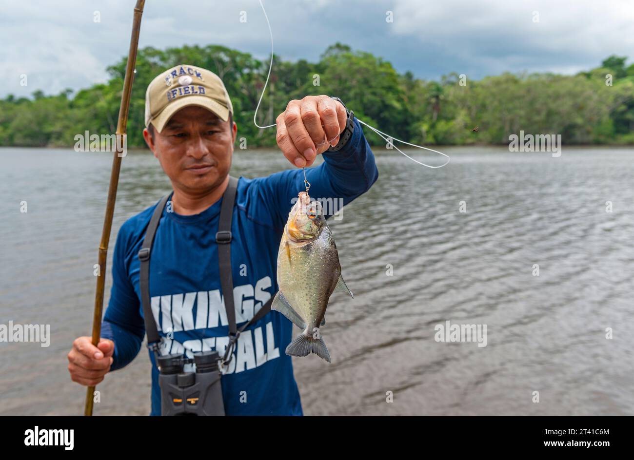Einheimischer Kichwa-Mann, der eine rothäuchliche Piranha (Pygocentrus nattereri auf lateinisch) am Haken anfischt, Yasuni-Nationalpark, Ecuador. Stockfoto