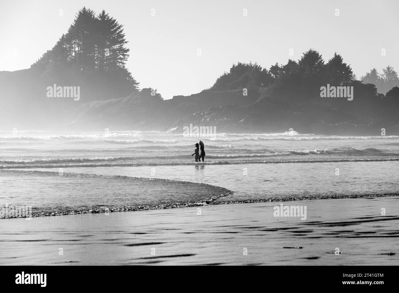 Silhouette von nicht erkennbaren Menschen, die in den Wellen des Pazifiks laufen, Tofino, Vancouver Island, British Columbia, Kanada. Stockfoto