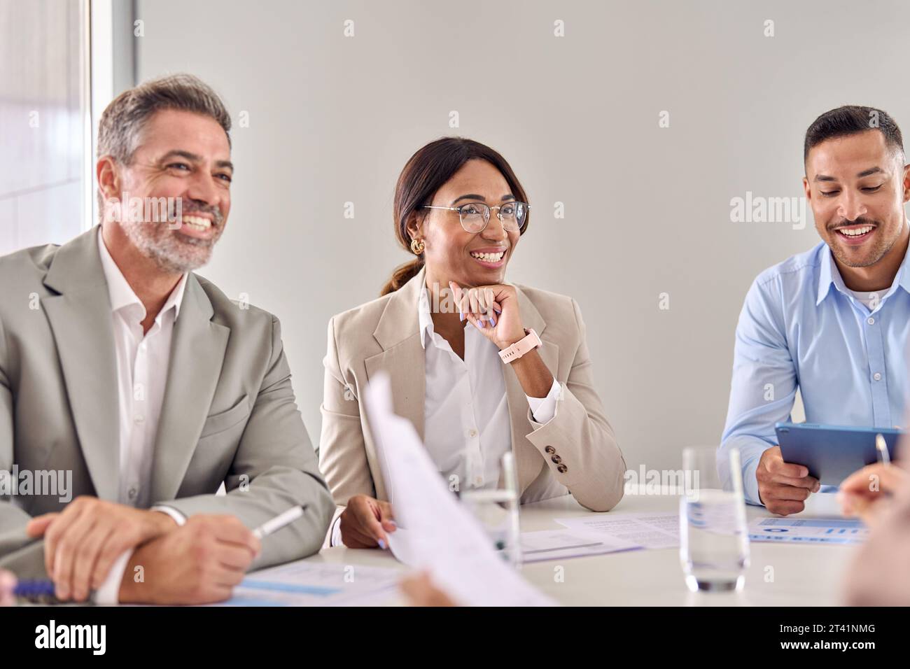 Glückliche Geschäftsfrau, die während eines Geschäftsgruppensitzes kommuniziert. Stockfoto