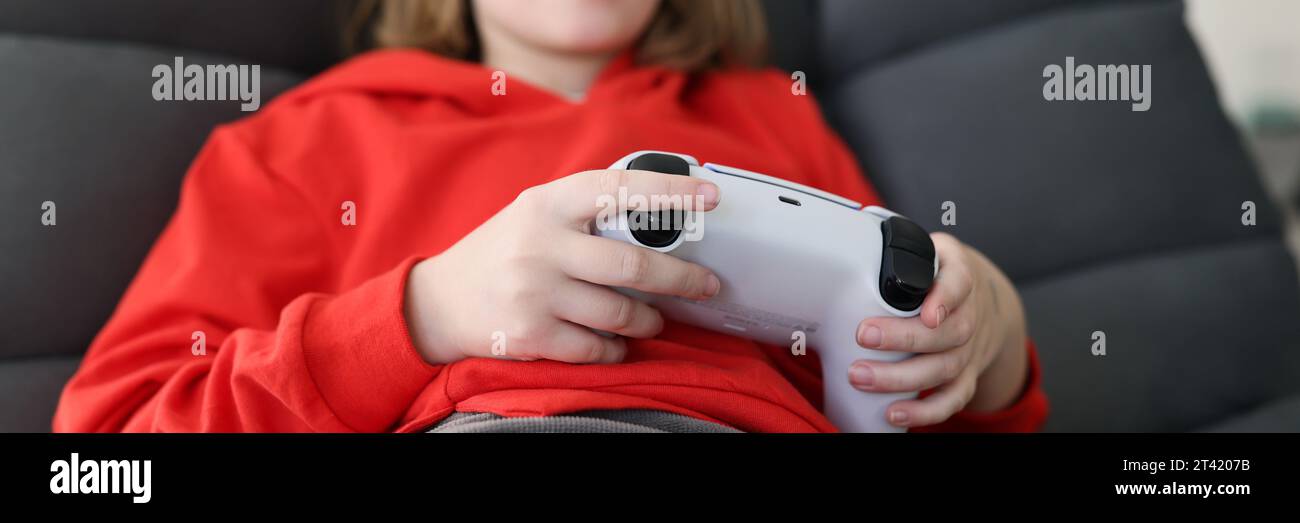 Fokussiertes Schulmädchen spielt Videospiele im Sessel Stockfoto