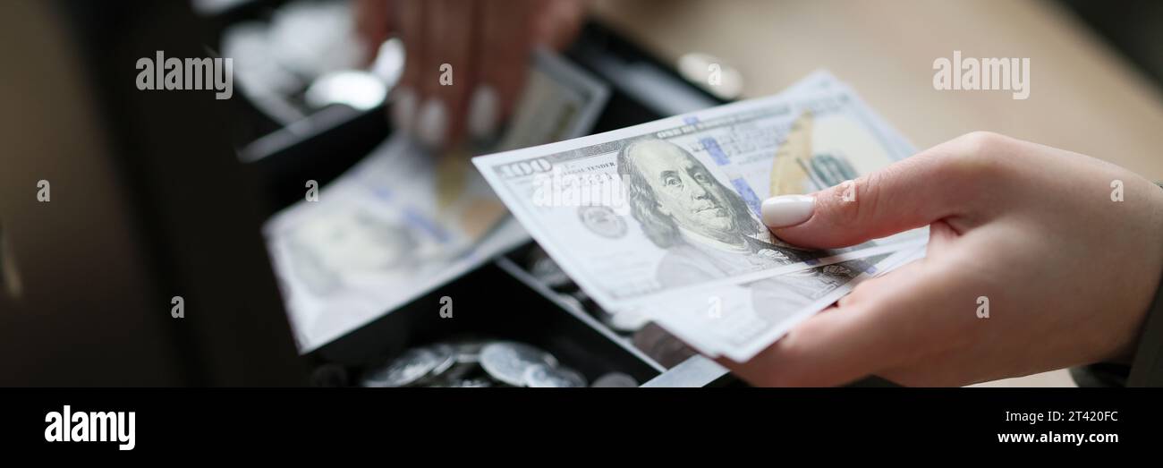 Der Buchhalter legt Dollars in die schwarze Kasse, um zu sparen Stockfoto
