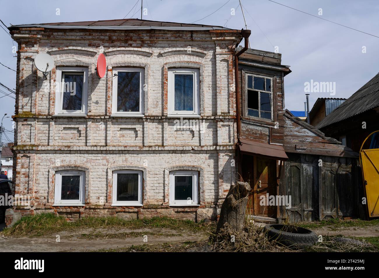 Ein altes, baufälliges Backsteinhaus mit einer hölzernen Verlängerung und Satellitenantennen Stockfoto