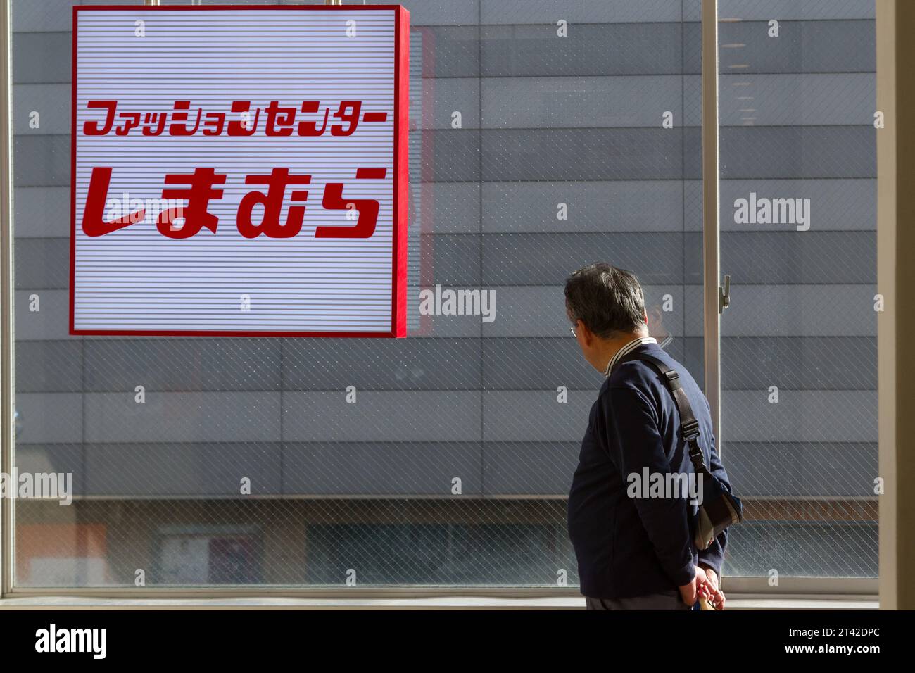 Ein älterer Japaner schaut aus einem Fenster mit einem beleuchteten Ladenschild. Yamato, Kanagawa, Japan. Stockfoto