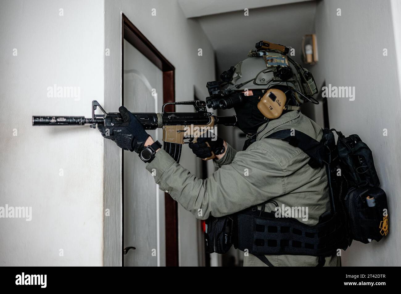 Ein Soldat der militärischen Spezialkräfte steht in einer Tür, während er Gebäude mit Nachtsicht räumt Stockfoto