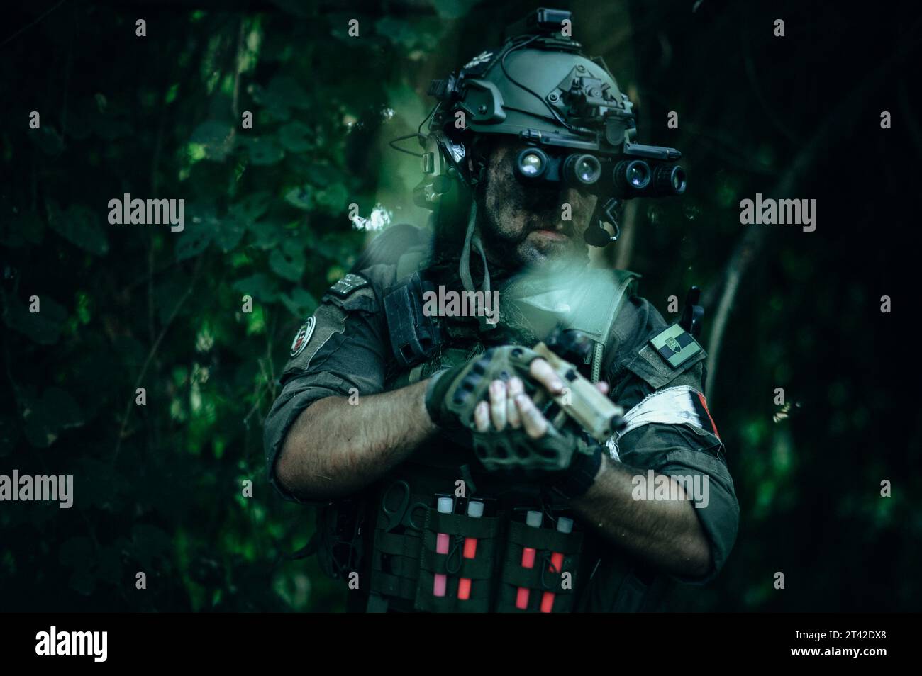 Ein Mann in schwarzer Militäruniform mit einem Sturmgewehr steht in einem dunklen Raum, beleuchtet von einem Paar leuchtend roter Augen Stockfoto