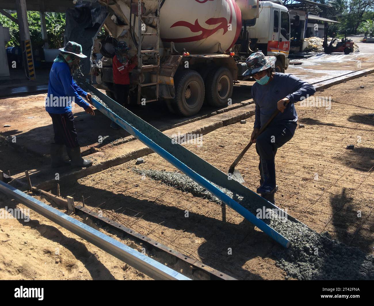 SURATTHANI, THAILAND - 12. Mai 2023 : die Arbeiter entladen Zement von LKWs und verteilen ihn in der Gegend. Dies ist der Prozess des Zementgießens Stockfoto