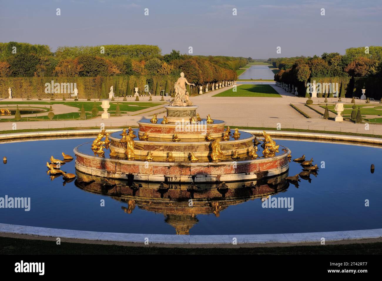Versailles: Latona (Latone) Brunnen leuchtet orange und großer Kanal kurz nach Sonnenaufgang im Garten und Park von Versailles, Ile-de-France, Frankreich Stockfoto