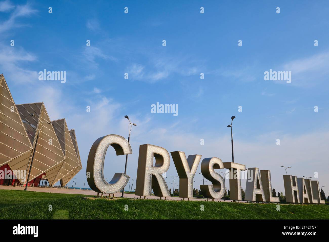 Blick auf das zerklüftete Äußere mit einem großen, ausgeschnittenen Schild auf dem vorderen Gras. Im Baku Kristallhalle-Arena-Gebäude in Baku, Aserbaidschan. Stockfoto