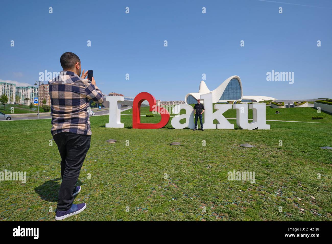 Touristen machen Fotos am ikonischen I Love Baku Schild, das auf dem Rasen vor dem Wahrzeichen des Gebäudes steht. Im Heydar Aliyev Centre Arts pe Stockfoto