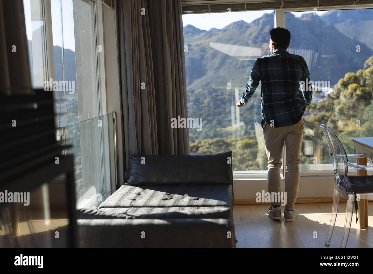 Rückansicht eines afroamerikanischen Mannes mit Blick auf die Berge vom Wohnzimmer aus, Kopierraum Stockfoto
