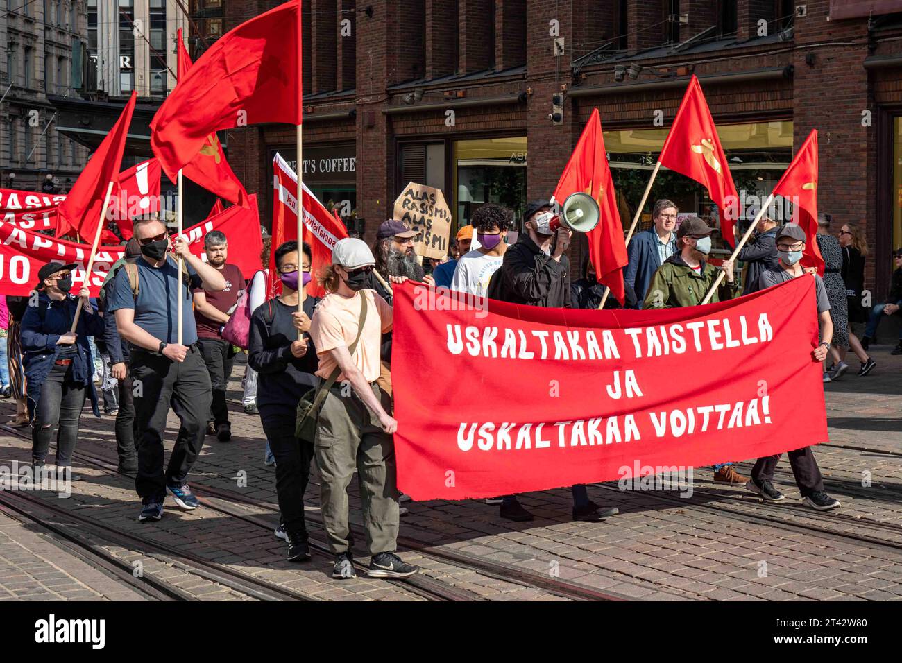 Maskierte Kommunisten mit roten Fahnen und Banner auf Aleksanterinkatu bei mir emme vaikene! Anti-Rassismus-Demonstration in Helsinki, Finnland Stockfoto
