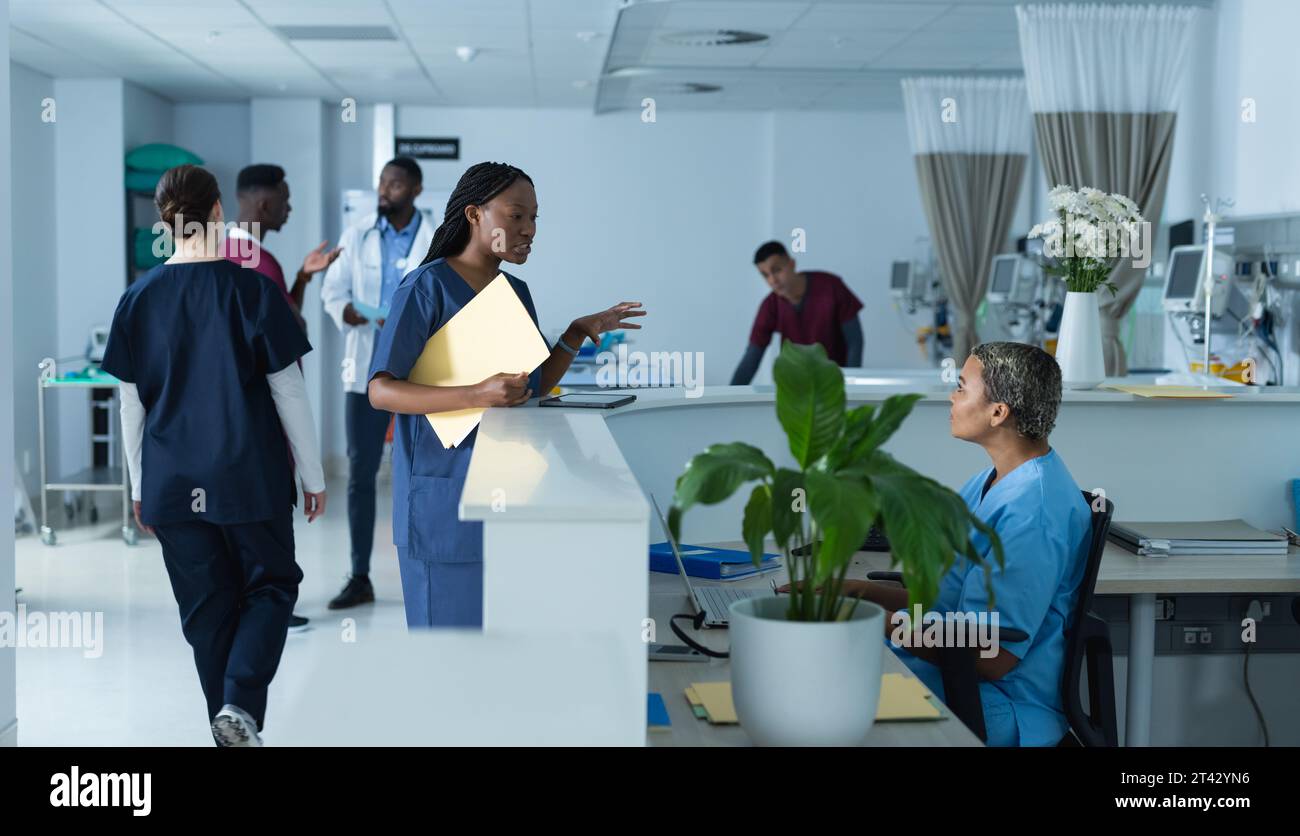 Diverse Ärztinnen diskutieren über die Arbeit an der Rezeption im Krankenhaus Stockfoto