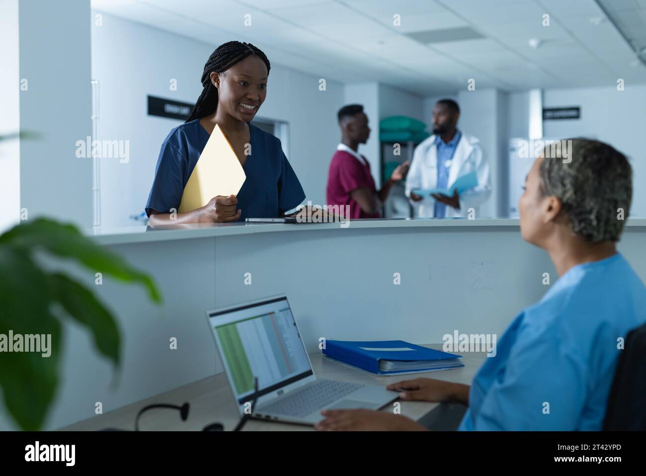 Diverse Ärztinnen diskutieren über die Arbeit an der Rezeption im Krankenhaus Stockfoto