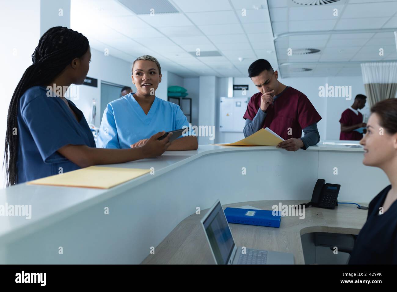 Verschiedene Ärztinnen diskutieren über Arbeit, mit Tablet an der Rezeption im Krankenhaus Stockfoto