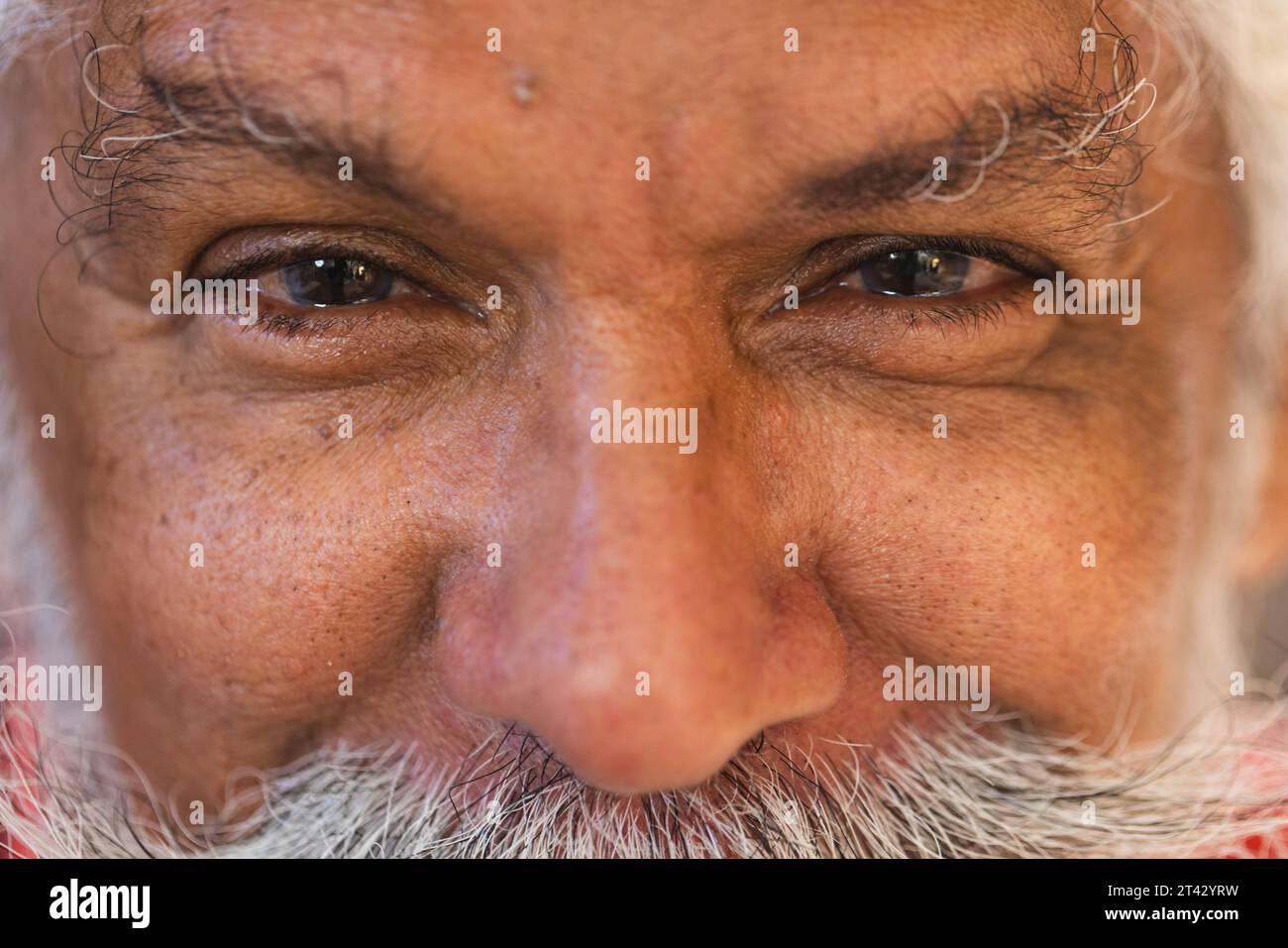 Augen eines glücklichen, birassischen Seniorenmannes mit langem Bart, lächelnd im Töpferstudio Stockfoto