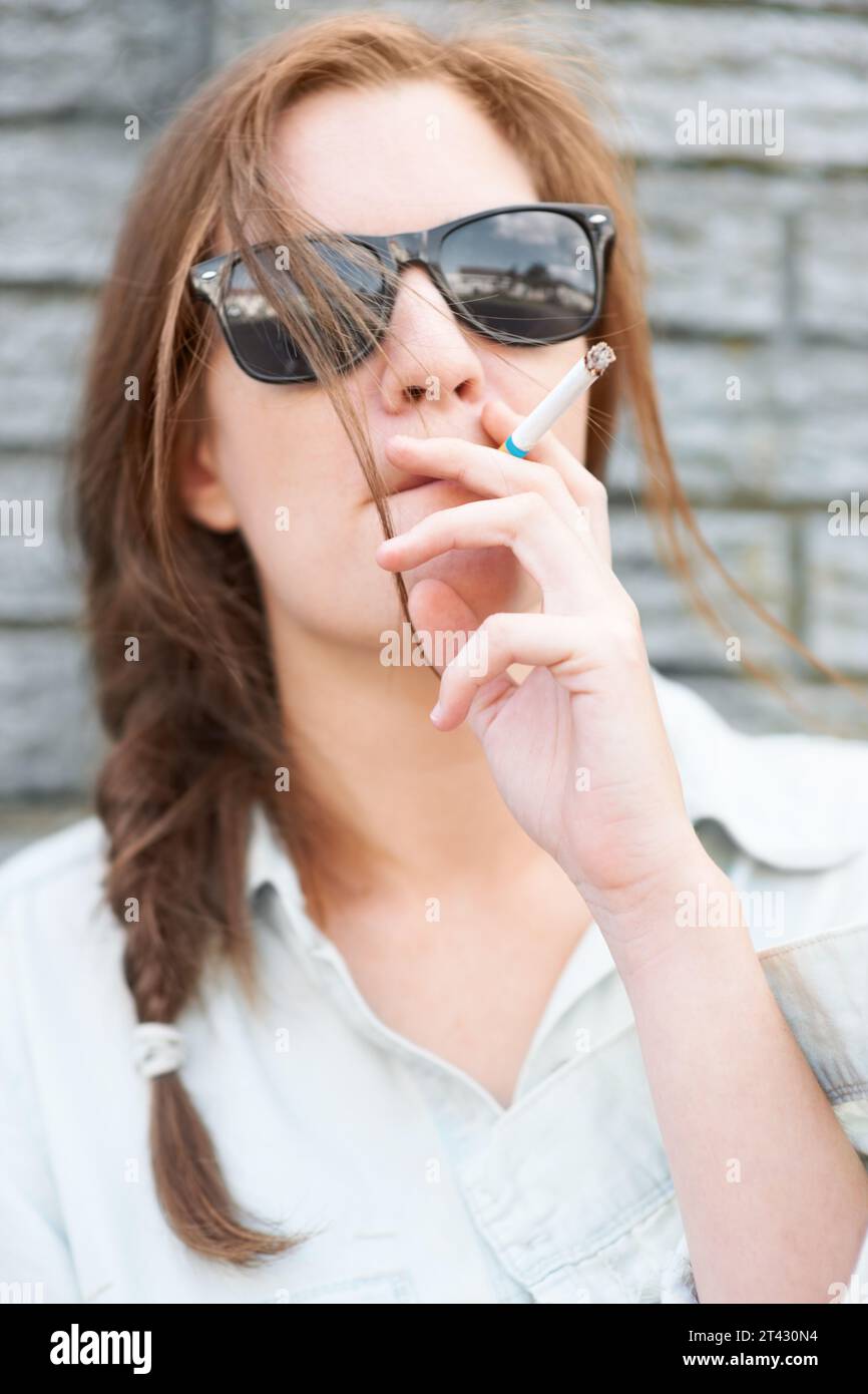 Cool, Stadt und eine Frau mit Sonnenbrille raucht mit Streetwear, stilvoll und urbaner Kultur. Mode, jung und ein Mädchen mit Rauch, Zigarette oder Stockfoto