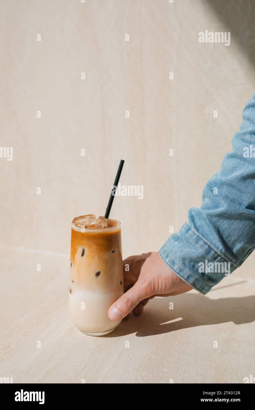Die Hand des Mannes greift nach einer Tasse Eiskaffee Stockfoto