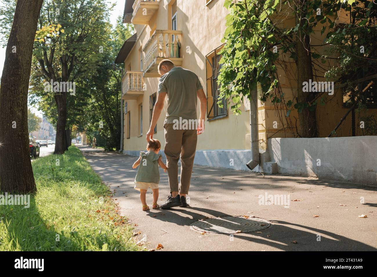 Rückansicht eines Mannes, der mit seiner Tochter Weißrussland die Straße entlang geht Stockfoto