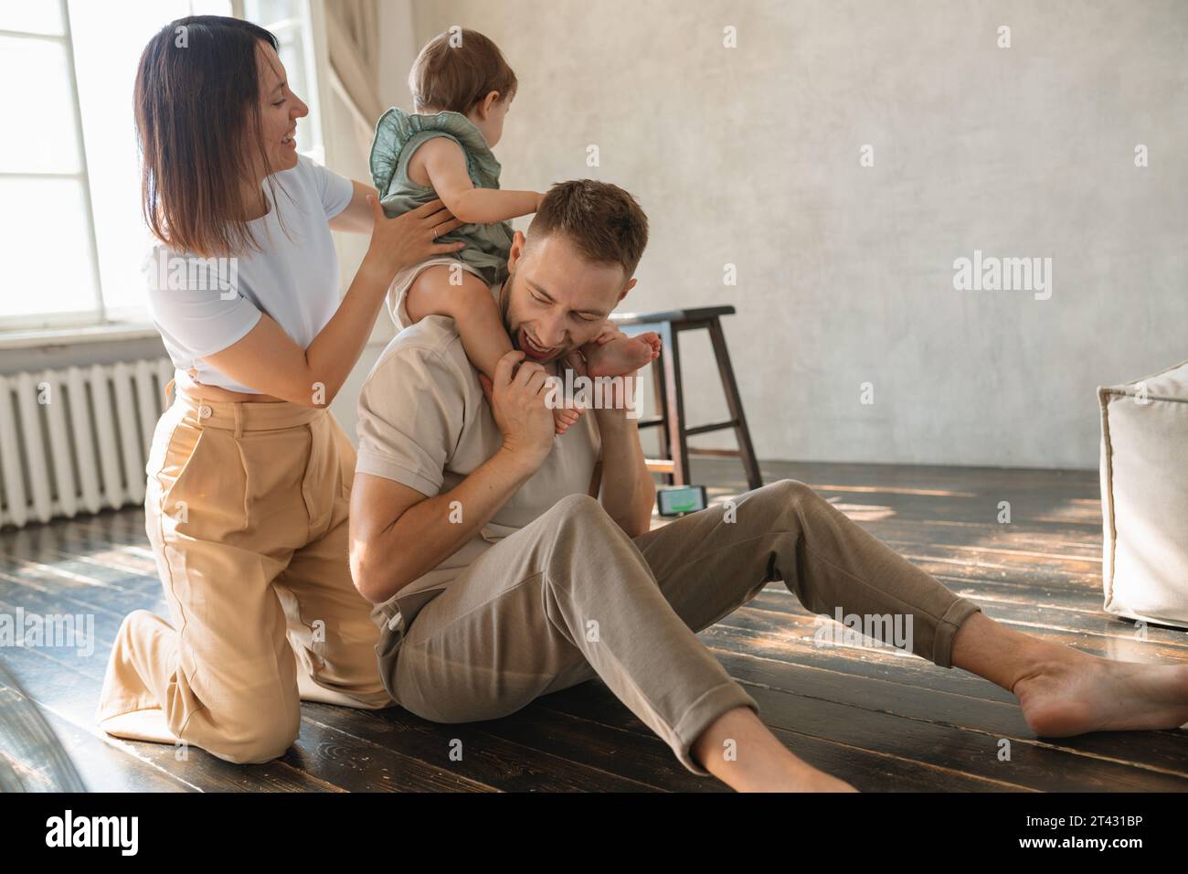 Ein junges Paar sitzt auf dem Boden in einem Wohnzimmer und spielt mit ihrer Tochter Stockfoto