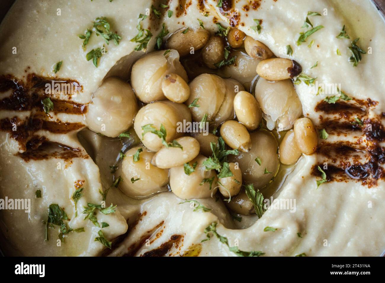 Vollformatansicht einer Schüssel Hummus mit Kichererbsen, Olivenöl und Gewürzen Stockfoto