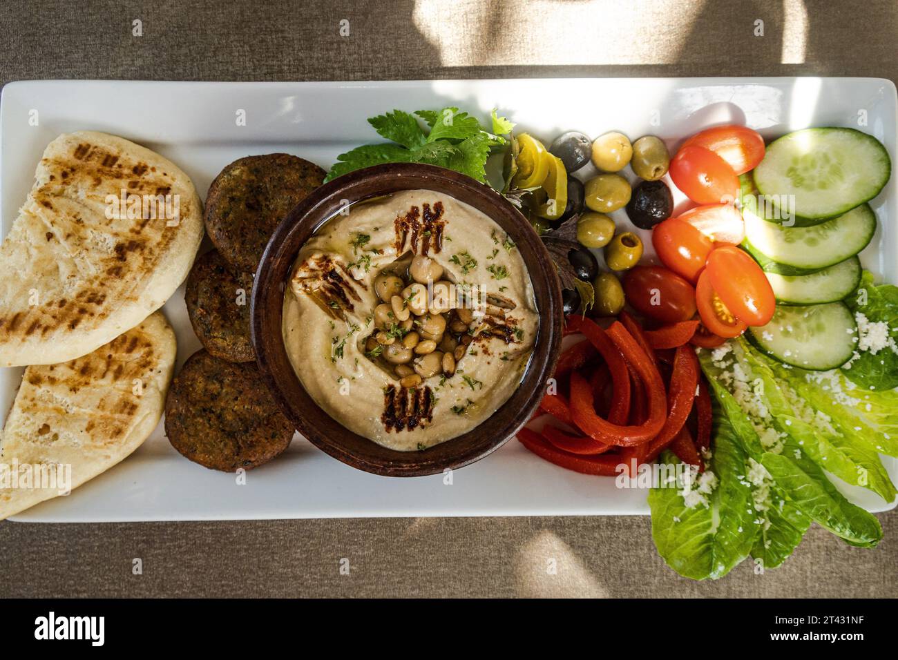 Blick von oben auf eine Meze-Platte mit Fladenbrot, Hummus, Falafel, Oliven, Tomaten, Gurke und Salat Stockfoto