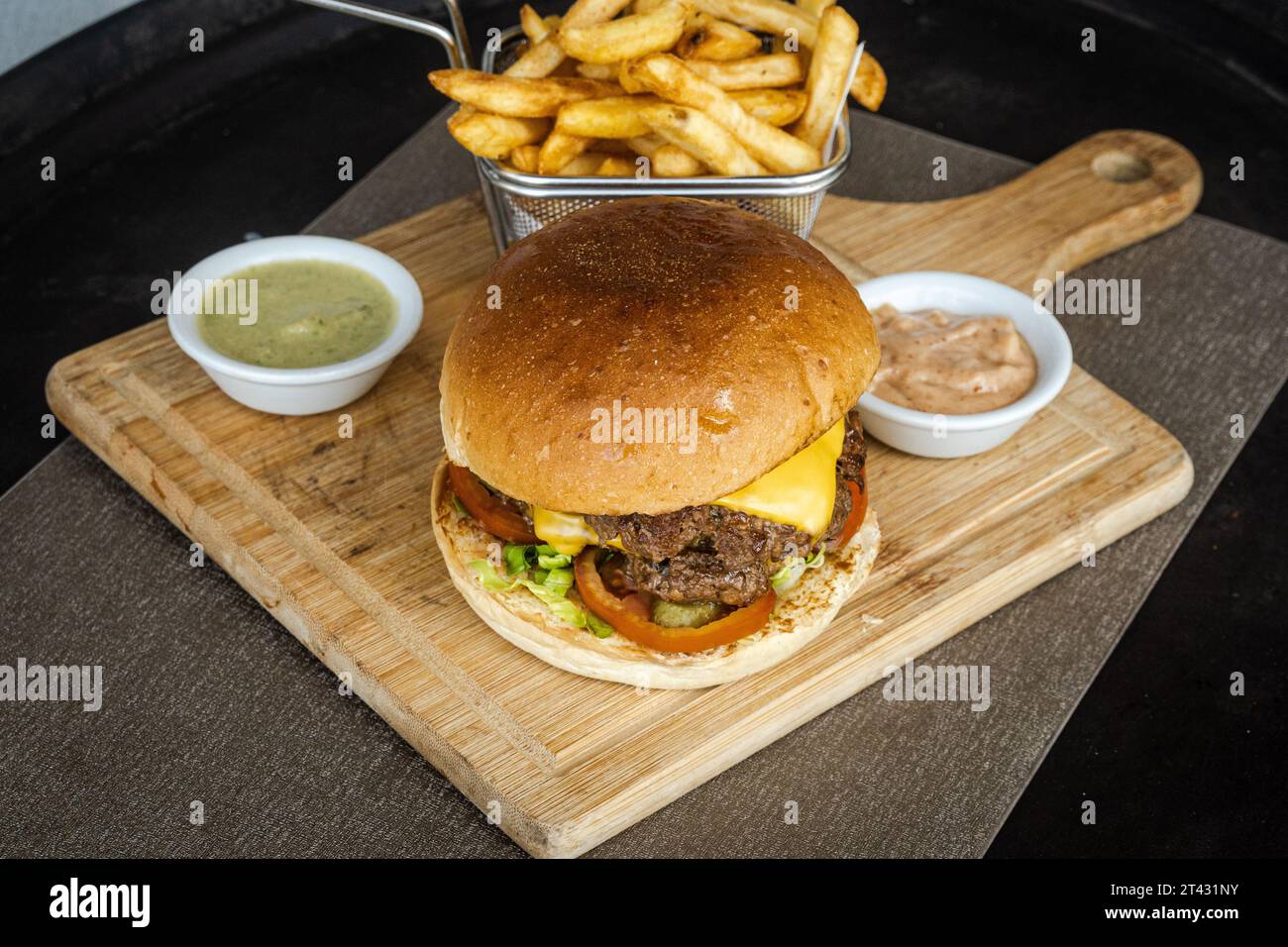 Nahaufnahme eines doppelten Cheeseburgers mit Chips und Saucen Stockfoto