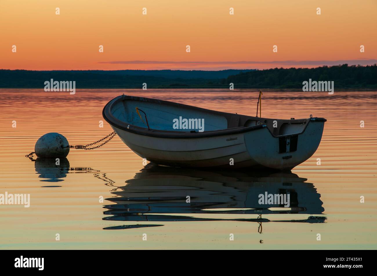 Intensiver und schöner Sonnenuntergang über dem See Finjasjön außerhalb von Hässleholm, Schweden, mit einem Boot und seinen Reflexen im Wasser. Stockfoto