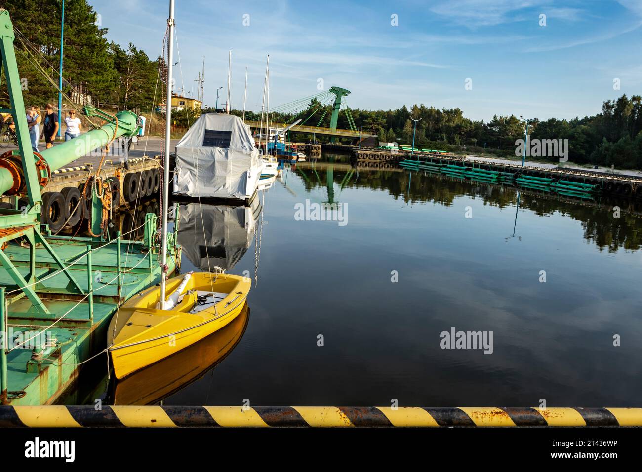 Mrzezyno, Polen - 10. September 2023: Kleines gelbes Segelboot, das im Hafenkanal verankert ist. Stockfoto