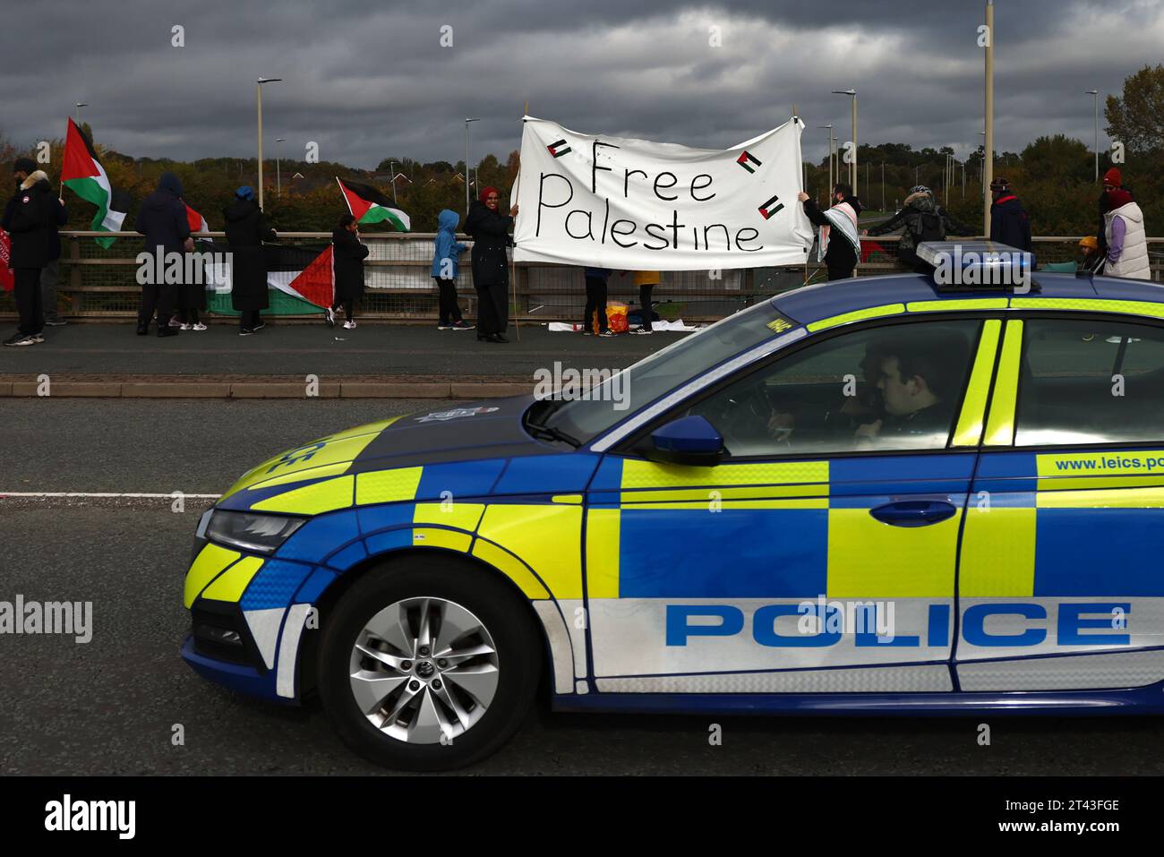 Leicester, Leicestershire, Großbritannien. Oktober 2023. Die Polizei kommt an Demonstranten vorbei, die während einer pro-palästinensischen Demonstration auf einer Straßenbrücke standen, und die Banner fallen in der Nähe der Basis der taktischen UAV-Systeme. UAV Tactical Systems ist ein israelisch-französisches Unternehmen, das Drohnen herstellt, die an die britische Armee, Israel und internationale Waffenmärkte verkauft werden. Credit Darren Staples/Alamy Live News. Stockfoto