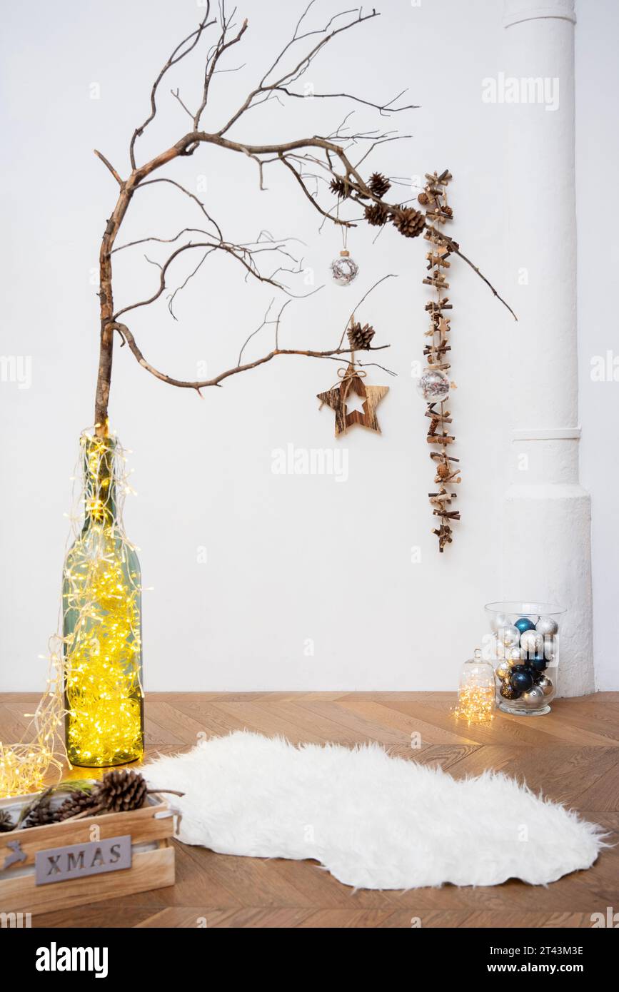 Erleben Sie den Zauber der Weihnachtszeit in einem Studio mit Ornamenten, Lichtern und einem rustikalen Zweig mit Tannenzapfen. Stockfoto