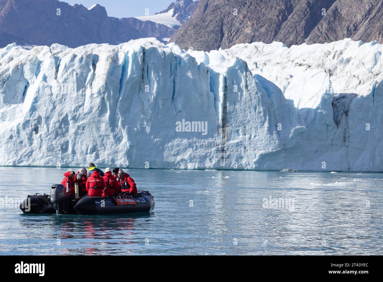Grönlandgletscher - Touristen in einem aufblasbaren Tierkreislauf, die einen Blick aus nächster Nähe auf den Thrym-Gletscher, einen Outlet-Gletscher, Skjoldungen-Fjord, Ostgrönland haben Stockfoto