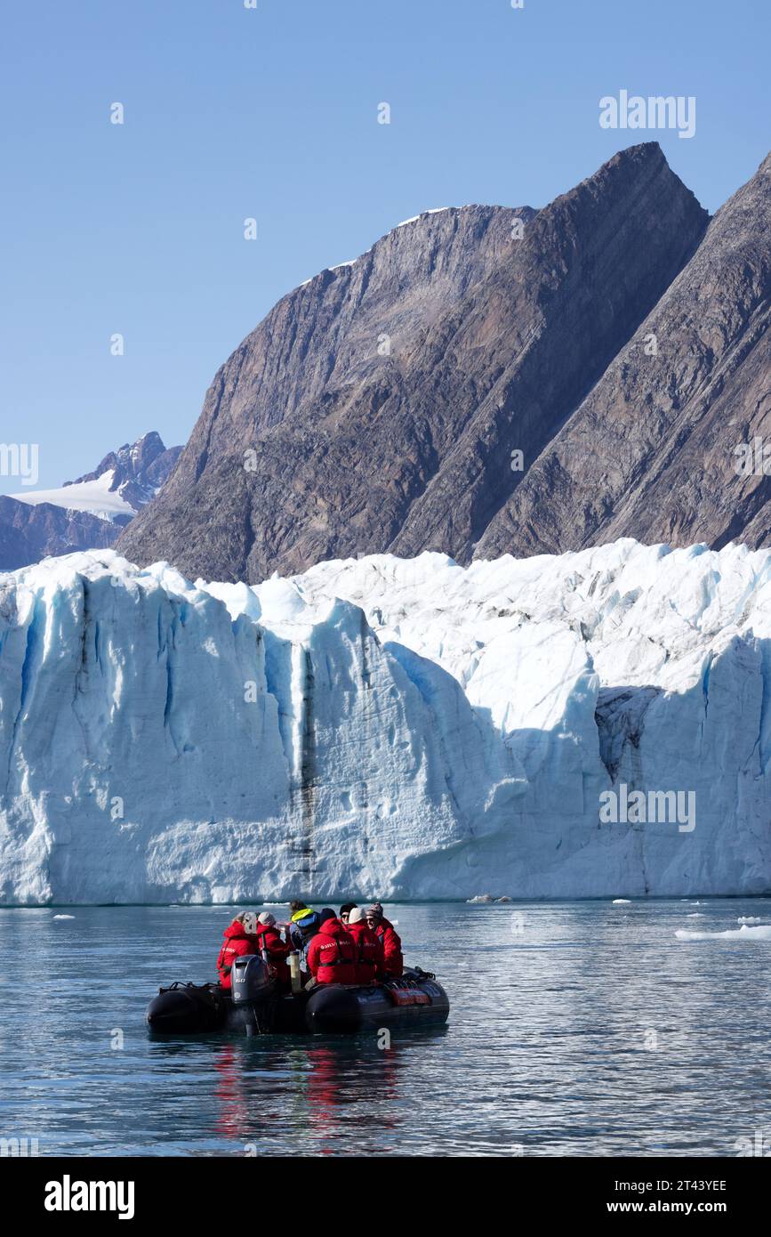 Grönlandgletscher - Touristen in einem aufblasbaren Tierkreislauf, die einen Blick aus der Nähe auf den Thrym-Gletscher, den Skjoldungen-Fjord, Ostgrönland haben. Reisen Sie In Die Arktis. Stockfoto