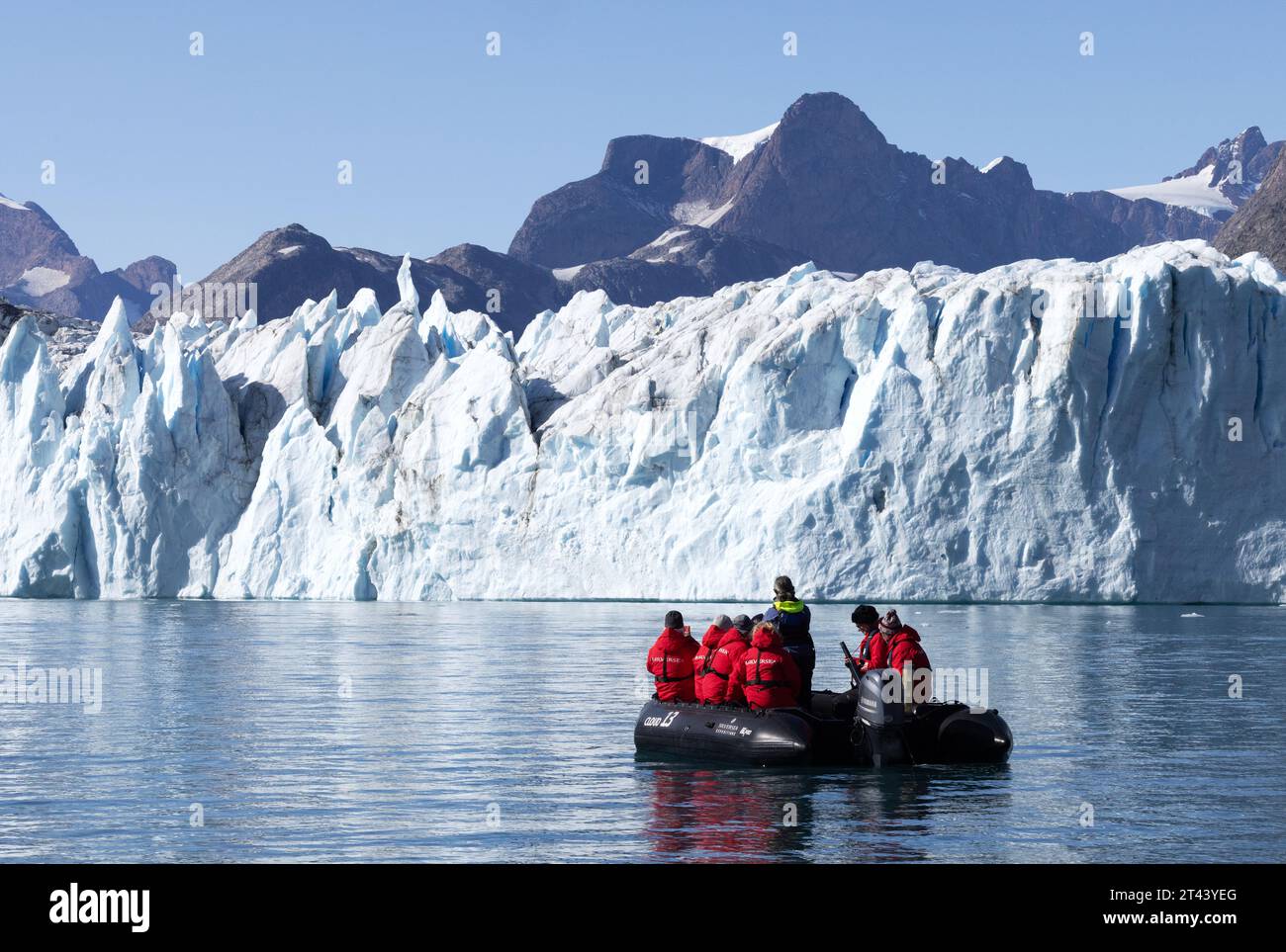 Abenteuerreise - Touristen in einem aufblasbaren Tierkreisboot, die einen Blick aus nächster Nähe auf den Thrym-Gletscher, den Skjoldungen-Fjord, Ostgrönland - Arctic Travel haben Stockfoto