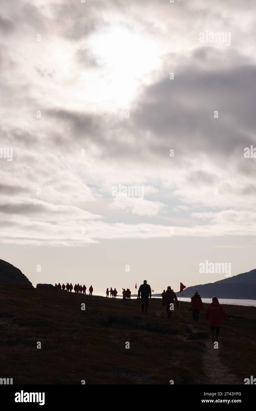 Grönland Touristen - Touristen Expedition Kreuzfahrtschiff Passagiere gehen in dramatische Landschaft und Himmel, Uunartoq, Südgrönland, Arktis. Stockfoto