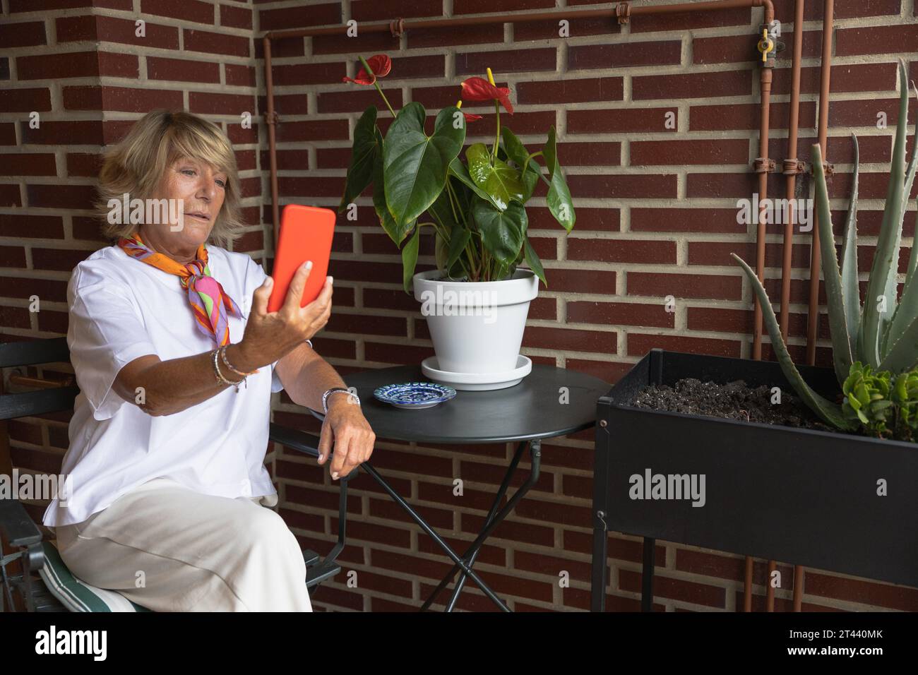 Reife Frau, die auf dem Balkon sitzt und ein Selfie macht Stockfoto