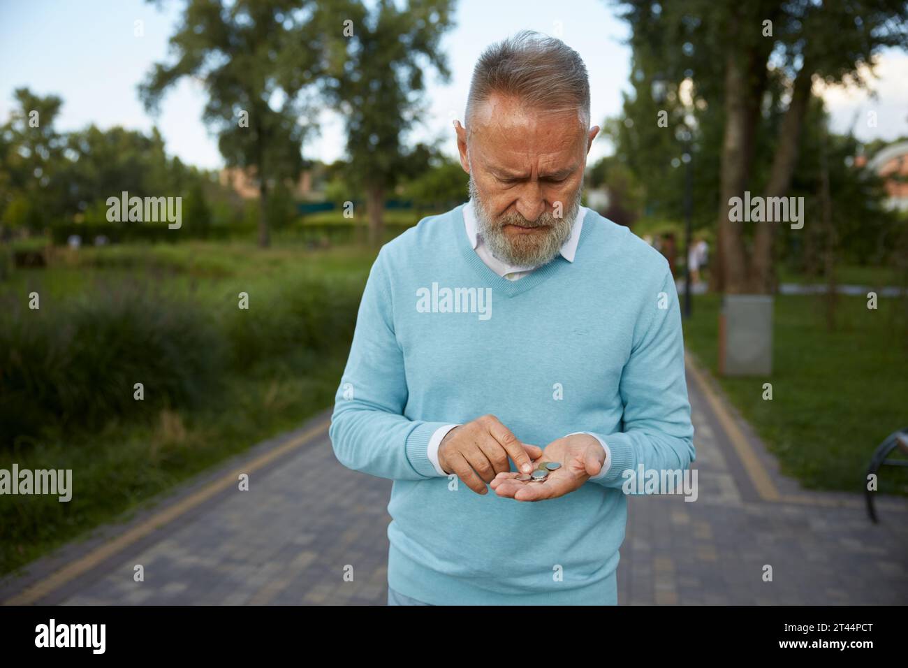 Konzentrierter Senior-Mann, der Münzen aus seiner Brieftasche zählt Stockfoto