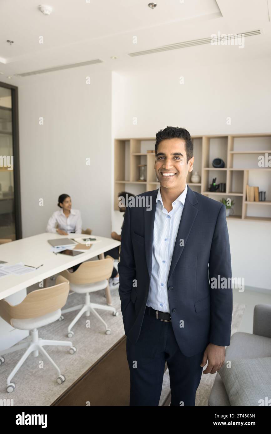 Ein glücklicher, erfolgreicher indischer Geschäftsmann posiert im Konferenzraum Stockfoto