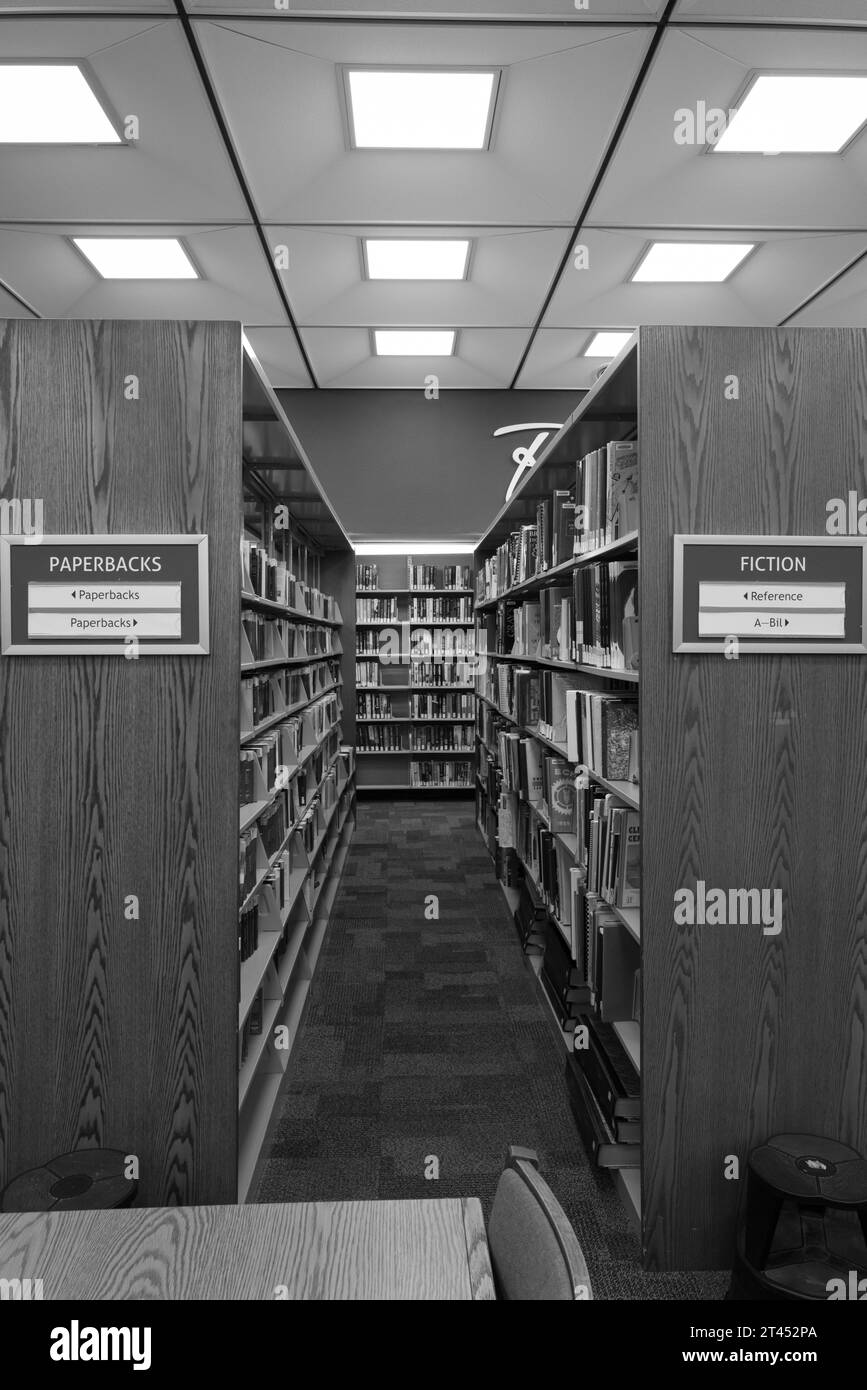 Bücherregale in einer öffentlichen Bibliothek mit Schildern mit Paperbacks und Fiction Stockfoto