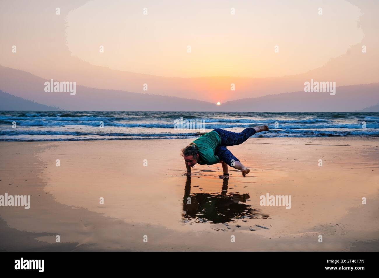 21-21-2019 Goa, IndiaYoga Lehrer steht in einer Pose (Asana) auf 2 Händen und Beinen zur Seite am Strand in Goa Stockfoto