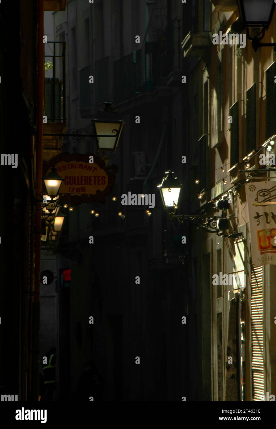 Eine Gasse im Viertel Raval von Barcelona mit Lichtern und Girlanden, die die Bars beleuchten. Stockfoto
