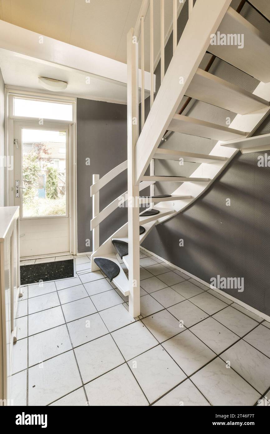 Ein leerer Raum mit weißen Treppen und Fliesenboden in der Mitte des Zimmers ist eine Treppe, die zum zweiten Stock führt Stockfoto
