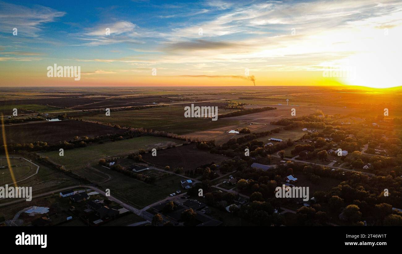 Ein Blick aus der Vogelperspektive auf einen atemberaubenden Sonnenuntergang über einer ländlichen Agrarlandschaft Stockfoto