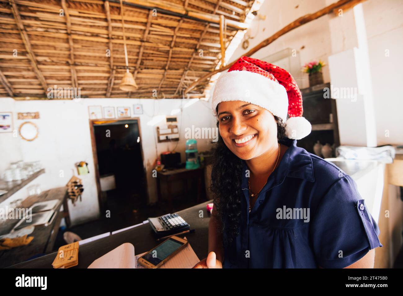 Eine lächelnde Einheimische trägt einen Weihnachtsmütze in einem Gästehaus in Tangalle, Sri Lanka Stockfoto