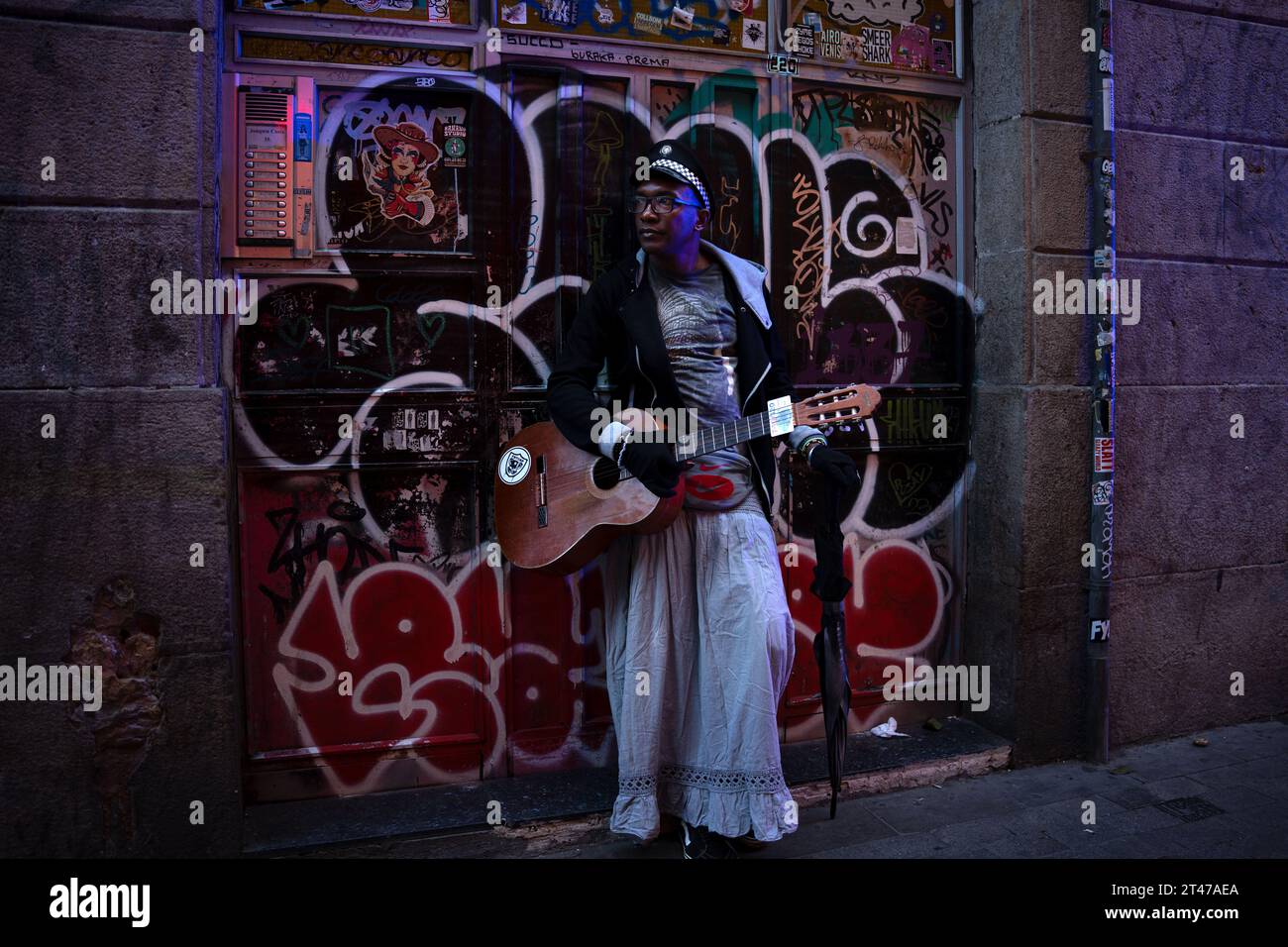 Barcelona, Spanien. Oktober 2023. Helio VAnimal, ein Musiker und Heiler, steht vor einer mit Aufklebern beputzten Tür in Barcelonas Viertel El Raval, während er pro-palästinensische Demonstranten beobachtet. Pro-palästinensische Demonstrationen erregten die Aufmerksamkeit aller Einheimischen und Straßenkünstler in Barcelonas Viertel El Raval. Quelle: SOPA Images Limited/Alamy Live News Stockfoto