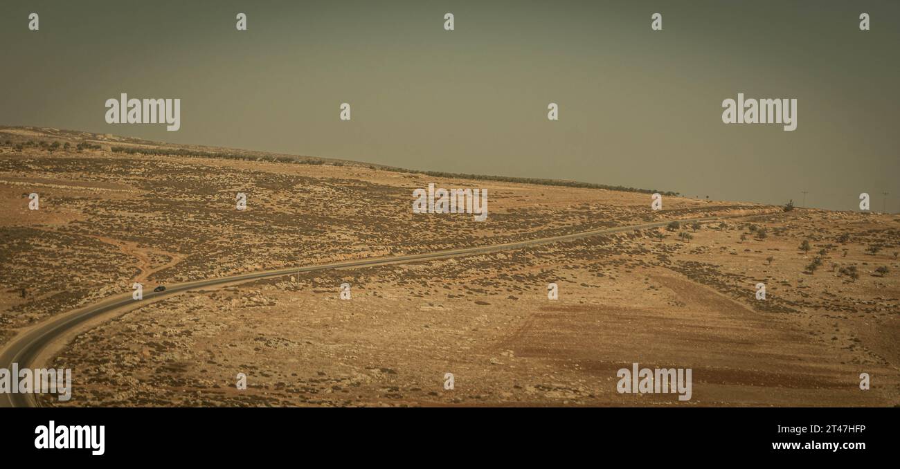 Die Straße führt durch die Sandwüste Negev in der Mitte des Westjordanlands, palästinensische Autonomie (Palästina) im Westjordanland. Stockfoto