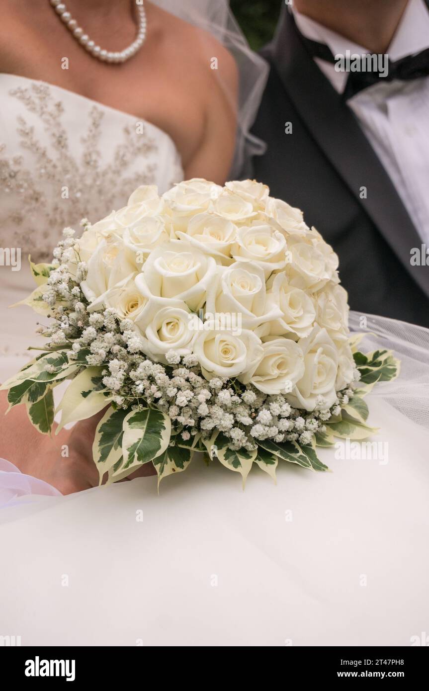 Ein Hochzeitsstrauß mit Rosen in den Händen der Braut und des Bräutigams neben ihr Stockfotografie