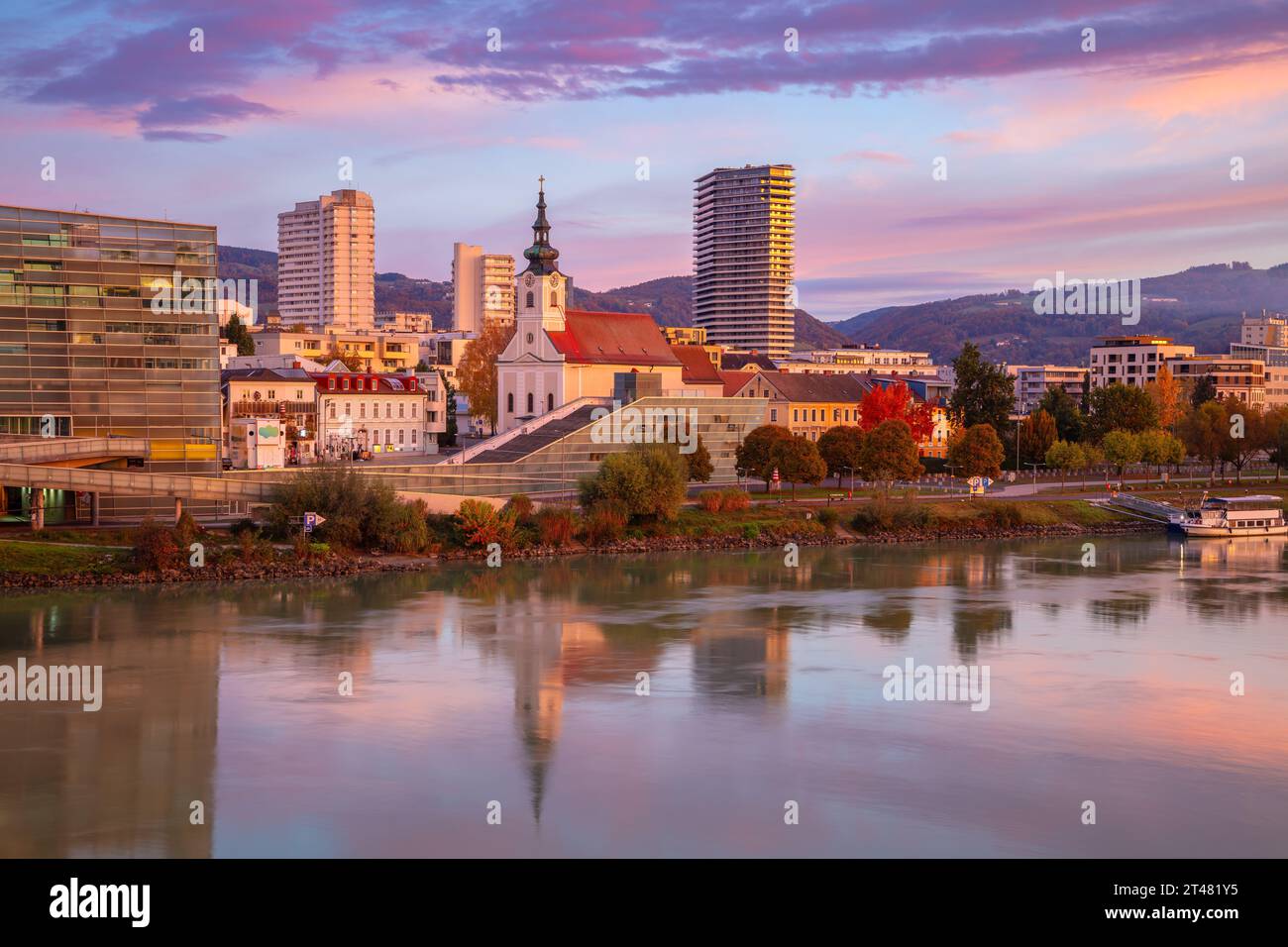Linz, Österreich. Stadtbild des Flusses Linz, Österreich bei schönem Sonnenaufgang im Herbst mit einer Reflexion der Stadt in der Donau. Stockfoto