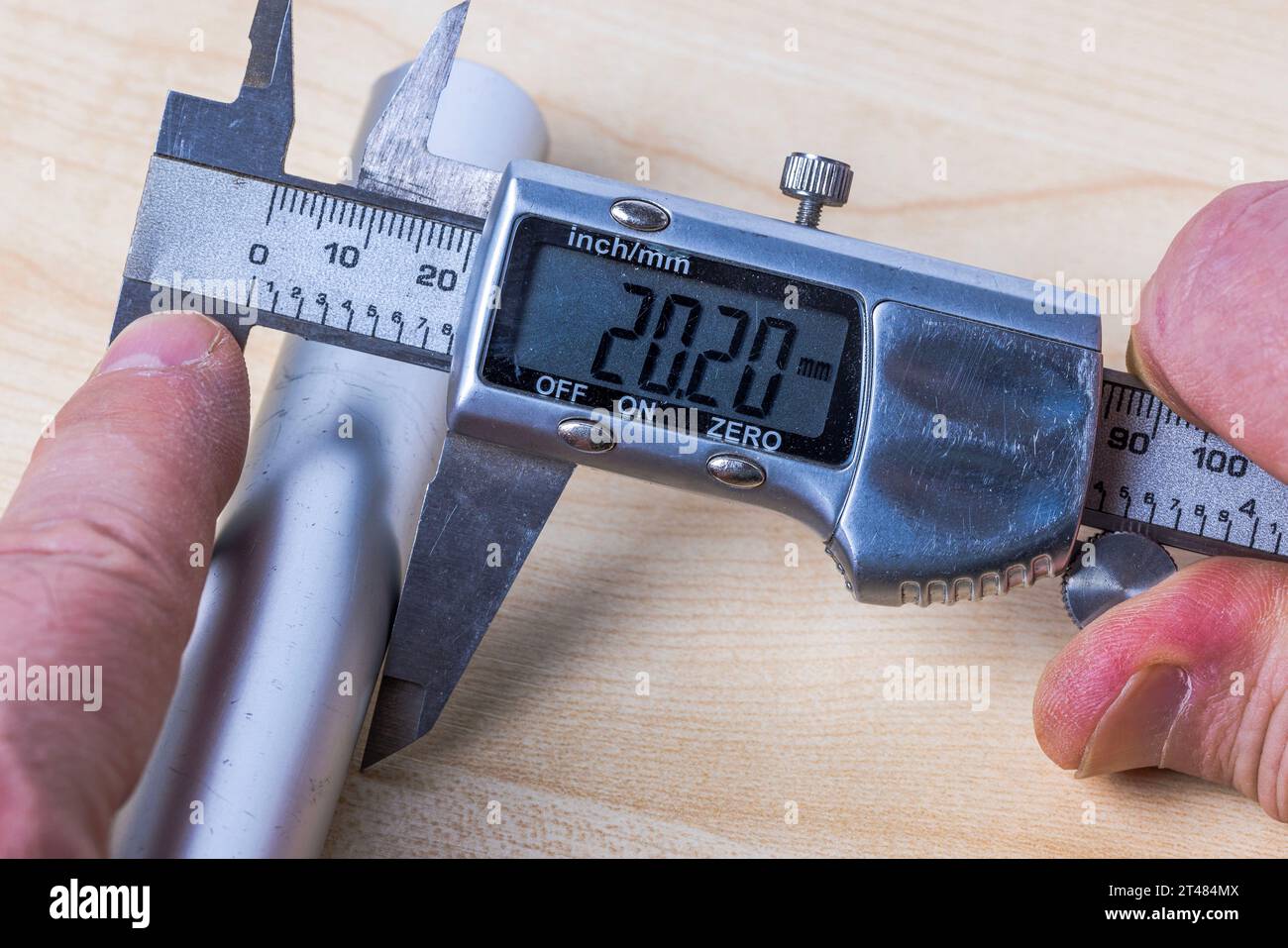 Man verwendet einen elektronischen Messschieber, um die Größe des Aluminiumrohrs zu messen. Stockfoto