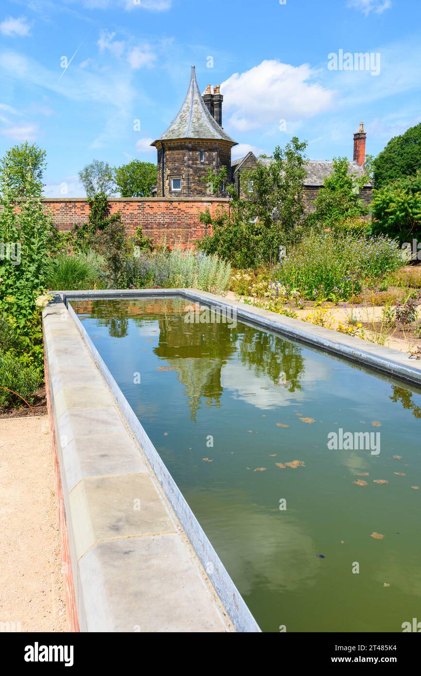 Das Garden Cottage spiegelt sich in einem Wasserspiel im Kitchen Garden in den RHS Bridgewater Gardens, Worsley, Salford, Greater Manchester, Großbritannien wider Stockfoto