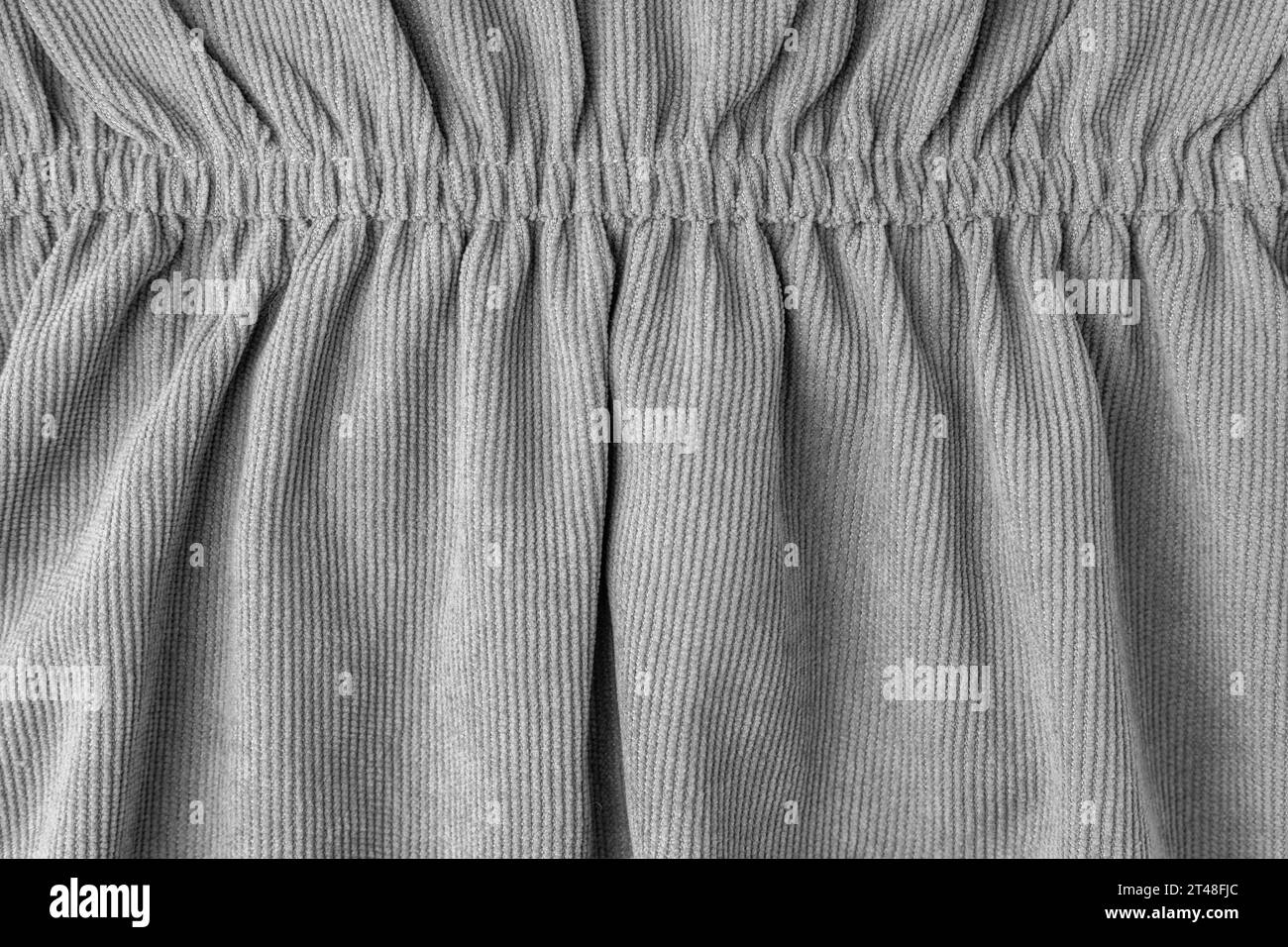 Graues Cordmaterial mit elastischer Nahaufnahme. Samtstruktur mit Falten und Vorhängen. Stoffoberfläche, Textilinhalt, Tapete, Hintergrund. Stockfoto